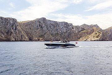 A boat is floating in the ocean with mountains in the background