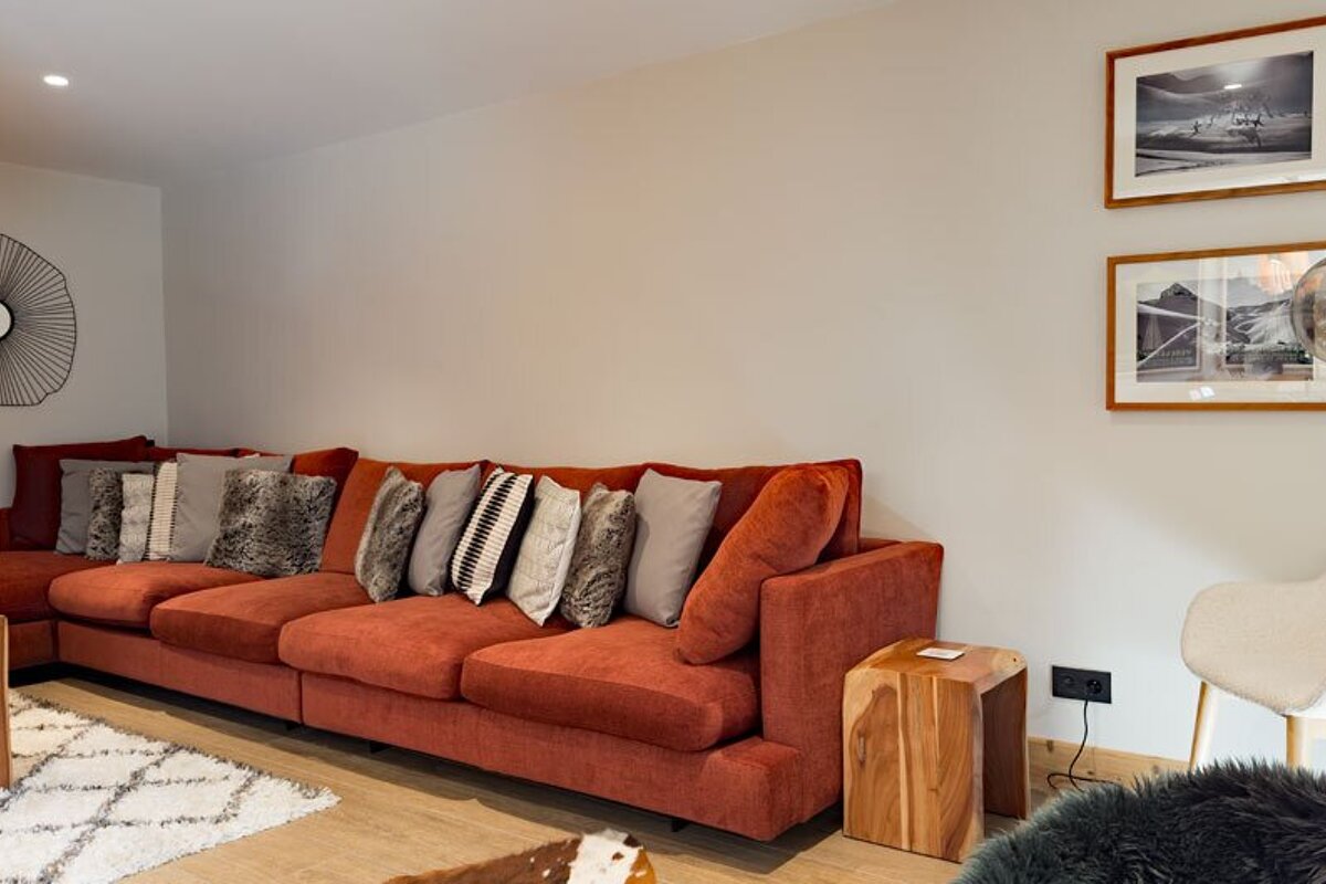 A living room with a red couch and two pictures on the wall