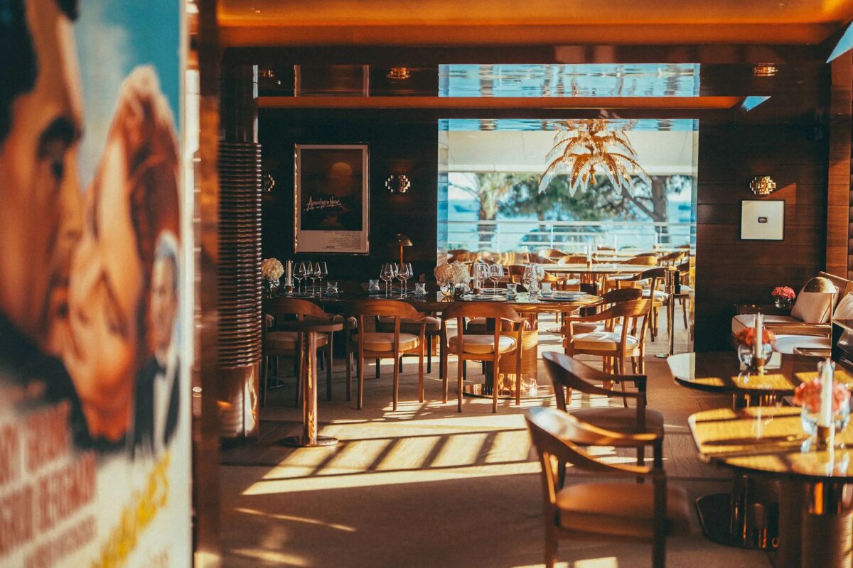 A restaurant with tables and chairs and a poster on the wall that says ' agatha '