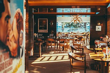A restaurant with tables and chairs and a poster on the wall that says ' agatha '