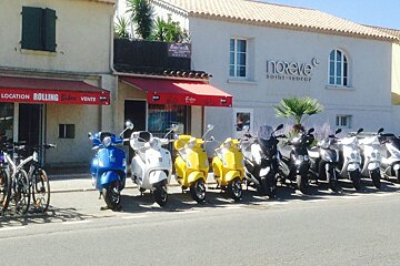 A row of scooters are parked in front of a store called noreve