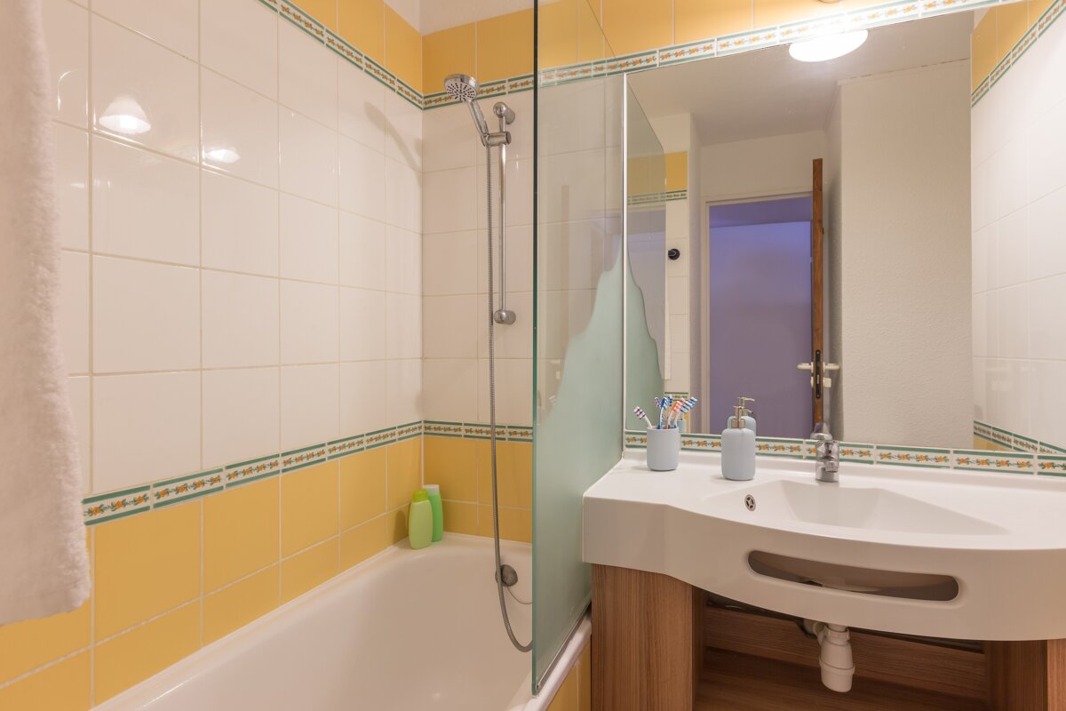 A bathroom with yellow and white tiles and a sink