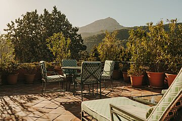 A patio with a table and chairs with a mountain in the background