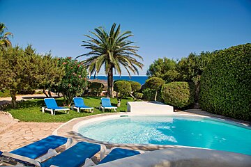 A swimming pool surrounded by blue chairs and palm trees