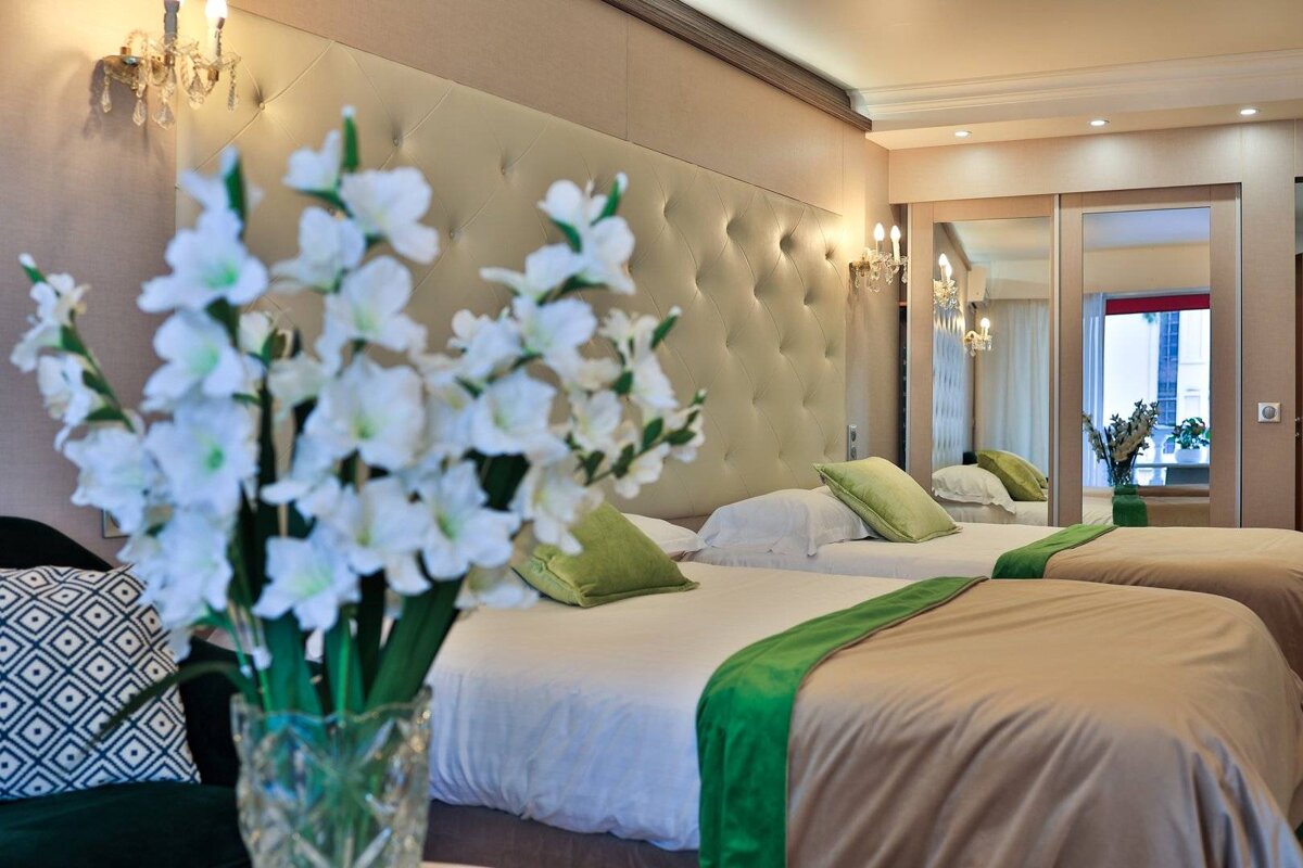 A hotel room with two beds and a vase of flowers