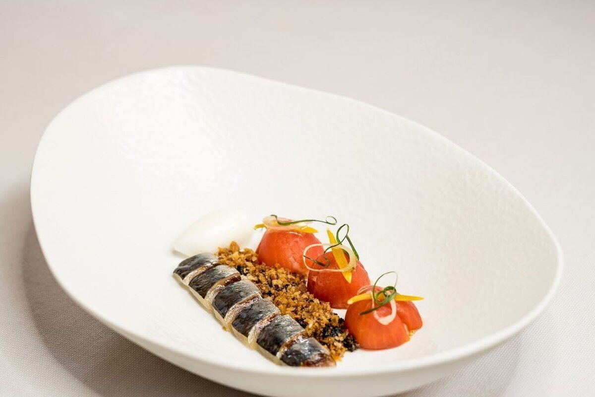 A white bowl filled with tomatoes and a piece of fish