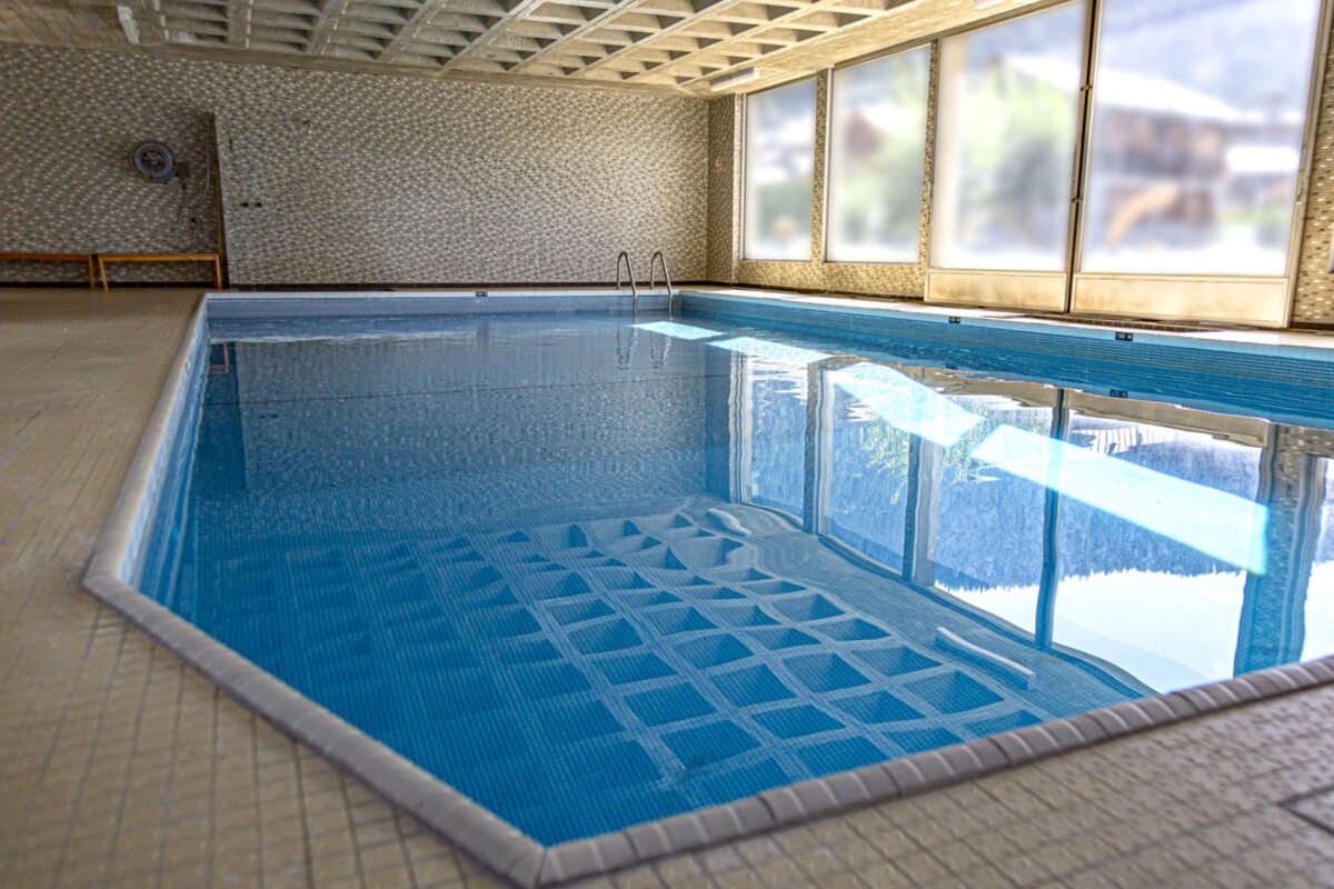 A large indoor swimming pool with a fan on the wall