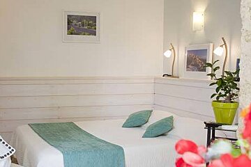 A bedroom with a bed , lamps , a potted plant and a mirror