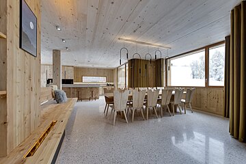 A wooden dining room with a long table and chairs