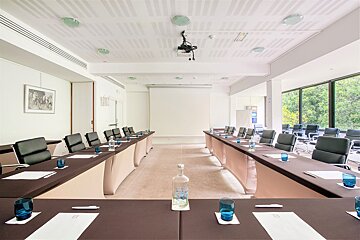 A conference room with long tables and chairs and a projector