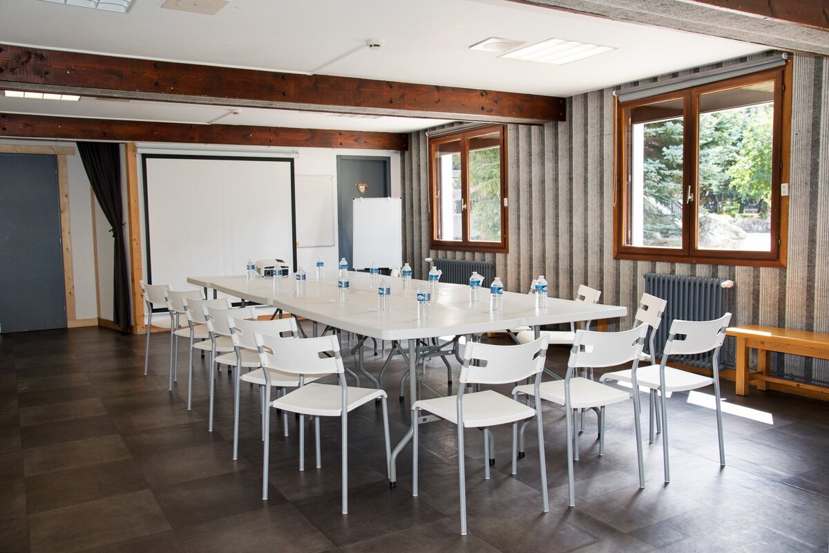 A room with a long table and chairs with bottles of water on it
