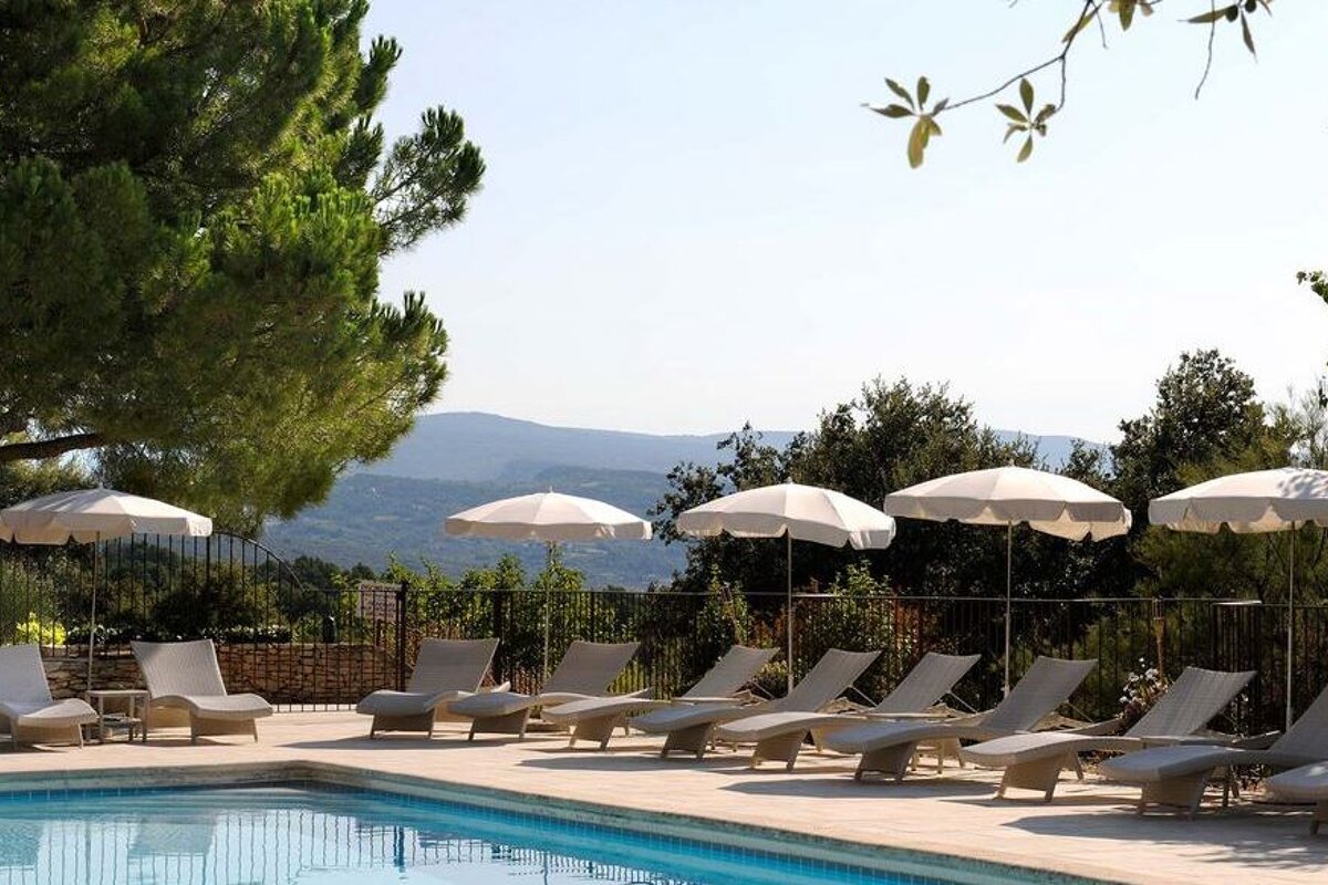 Pool with stone terrace surrounding with cream deck chairs and umbrellas