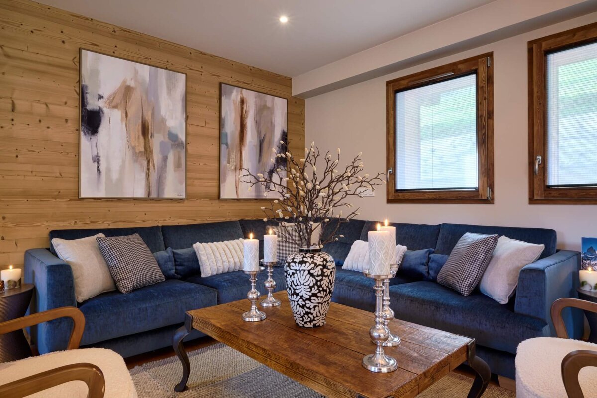A living room with a blue couch and a vase of flowers