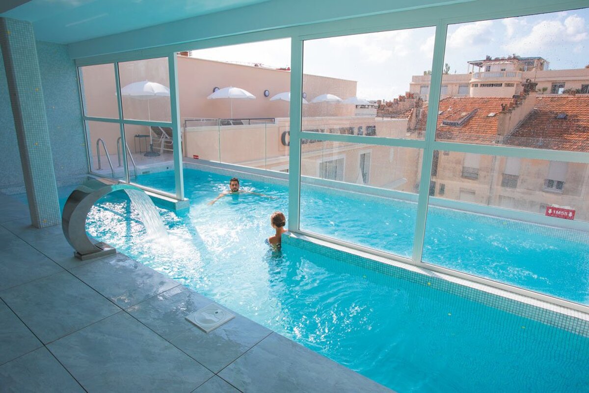 Two people are swimming in a swimming pool with a sign that says danger