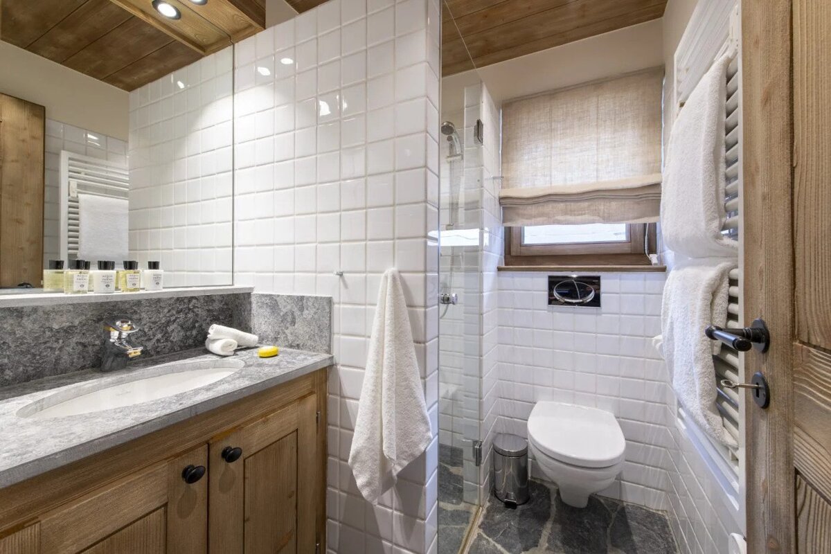 A bathroom with white tiles and a toilet