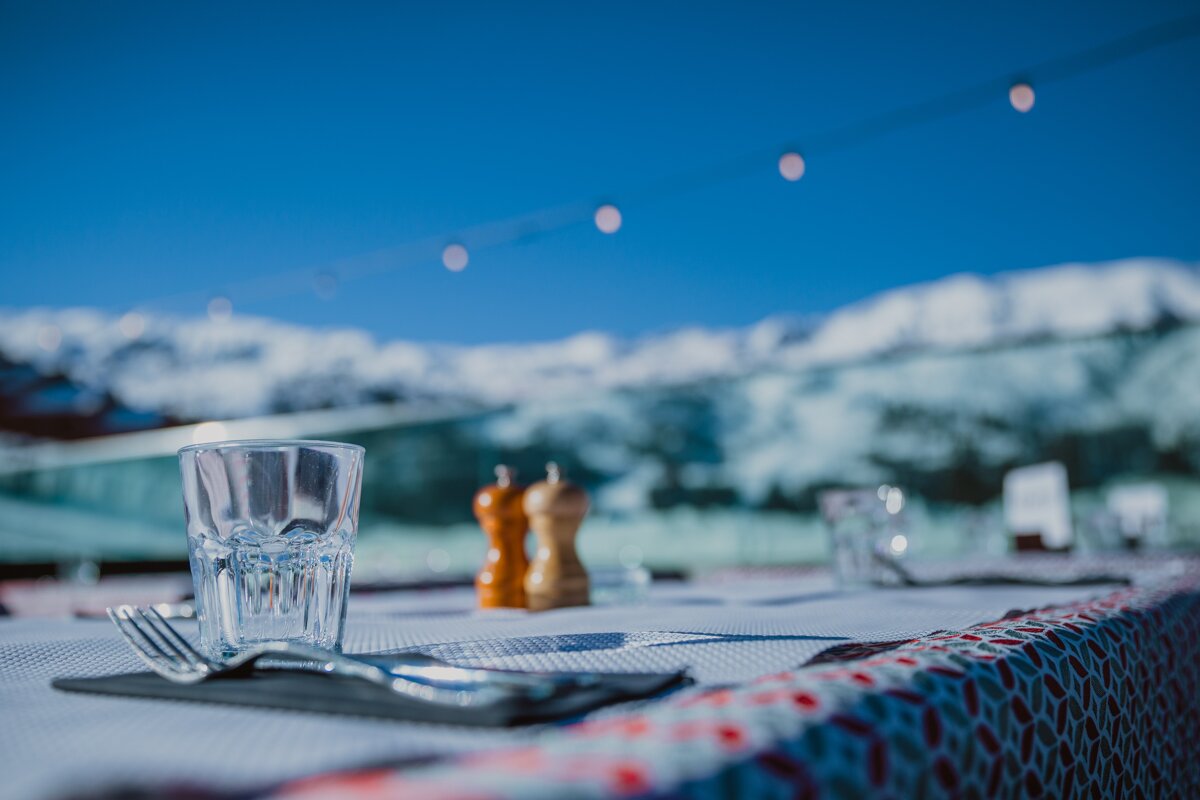 A glass of water sits on a table with mountains in the background