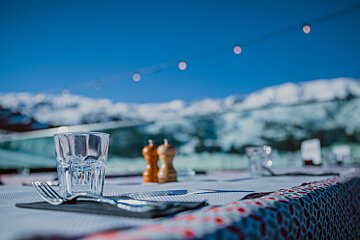 A glass of water sits on a table with mountains in the background