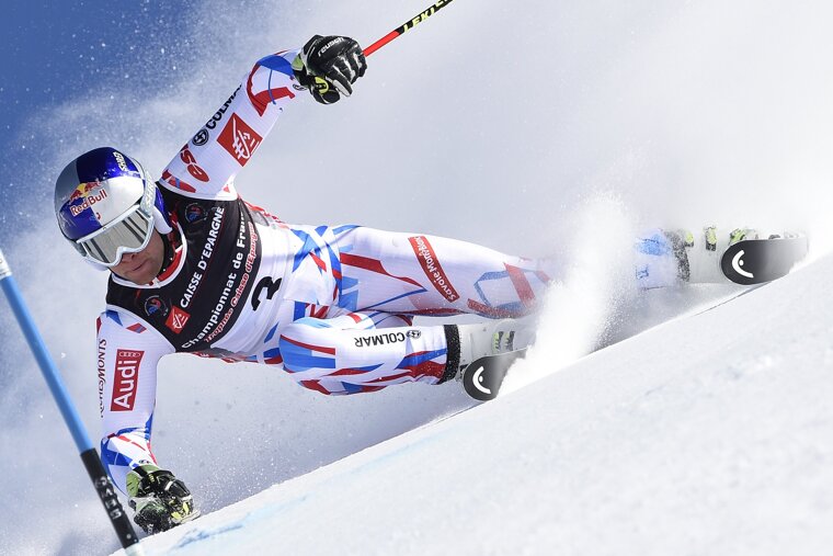 A skier wearing a red bull shirt is skiing down a snowy slope