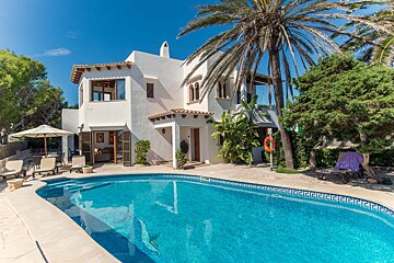 A white house with a swimming pool in front of it