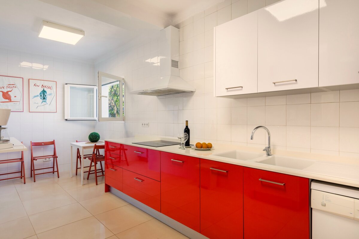 A kitchen with red cabinets and white counter tops