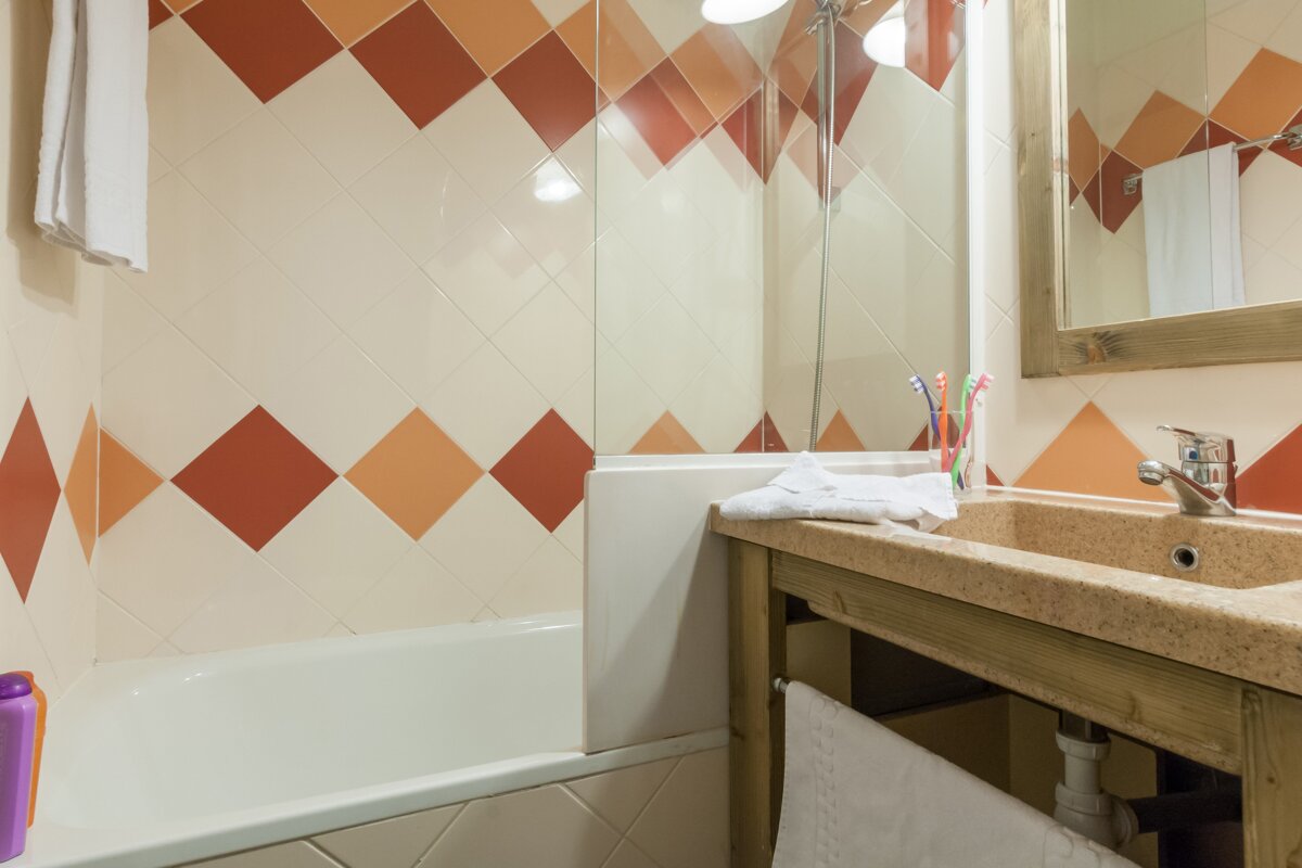 A bathroom with red and white tiles and a sink