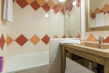 A bathroom with red and white tiles and a sink