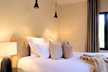 A bed with white sheets and pillows in a bedroom