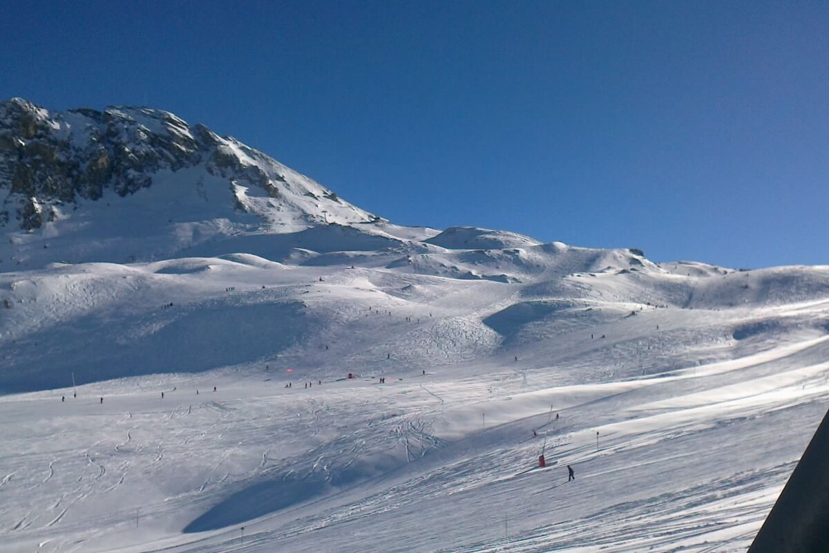 Skiers on a snowy slope with a mountain in the background