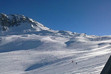 Skiers on a snowy slope with a mountain in the background
