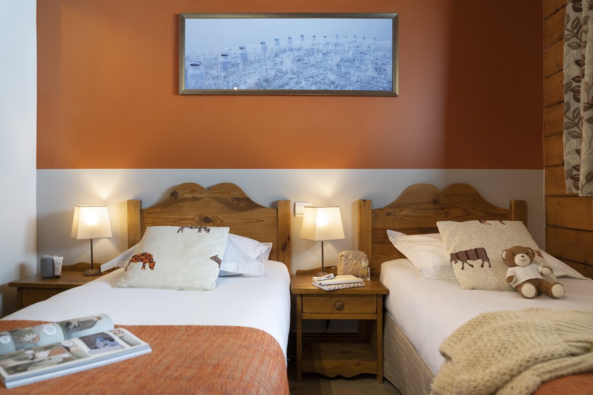 A bedroom with two beds and a picture on the wall above them