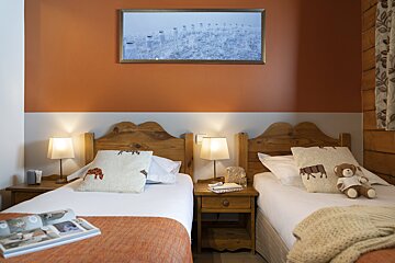 A bedroom with two beds and a picture on the wall above them