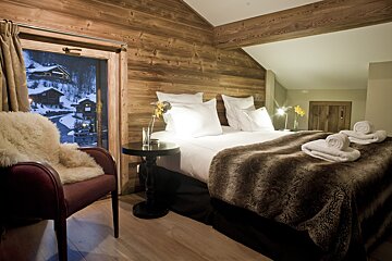 A bedroom with a large bed and a chair