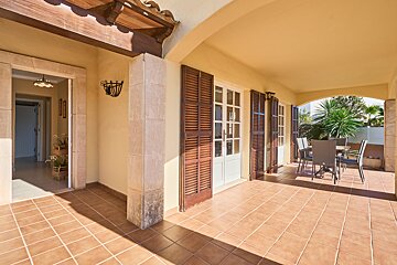A patio with a table and chairs and wooden shutters