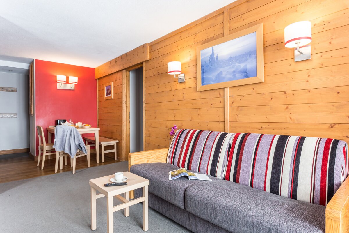 A living room with a striped couch and a painting on the wall