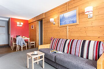 A living room with a striped couch and a painting on the wall