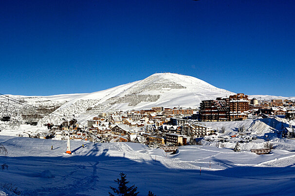 A snowy ski resort with a mountain in the background