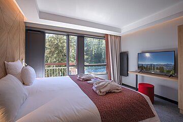 A hotel room with a large bed and a flat screen tv