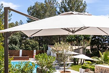 A large white umbrella is hanging over a swimming pool
