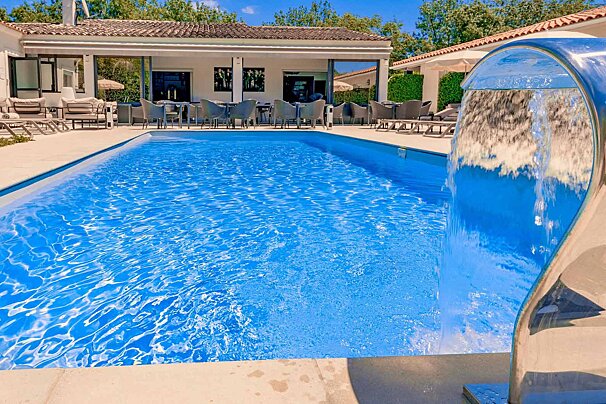 A large swimming pool with a waterfall in the middle