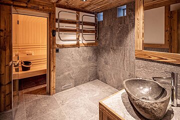 A bathroom with a stone sink and a wooden sauna