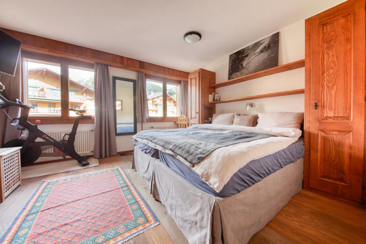 A bedroom with a bed and a peloton bike