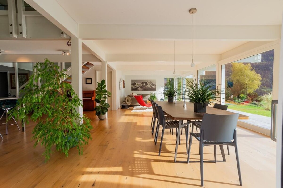 A dining room with a table and chairs and potted plants