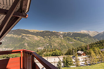 A view of the mountains from a balcony with a red railing