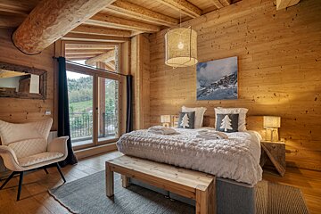 A bedroom with a large bed and a chair