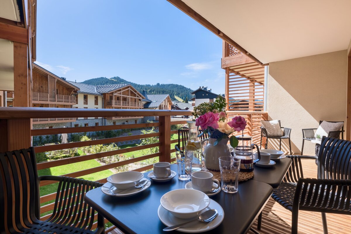 A table and chairs on a balcony with mountains in the background