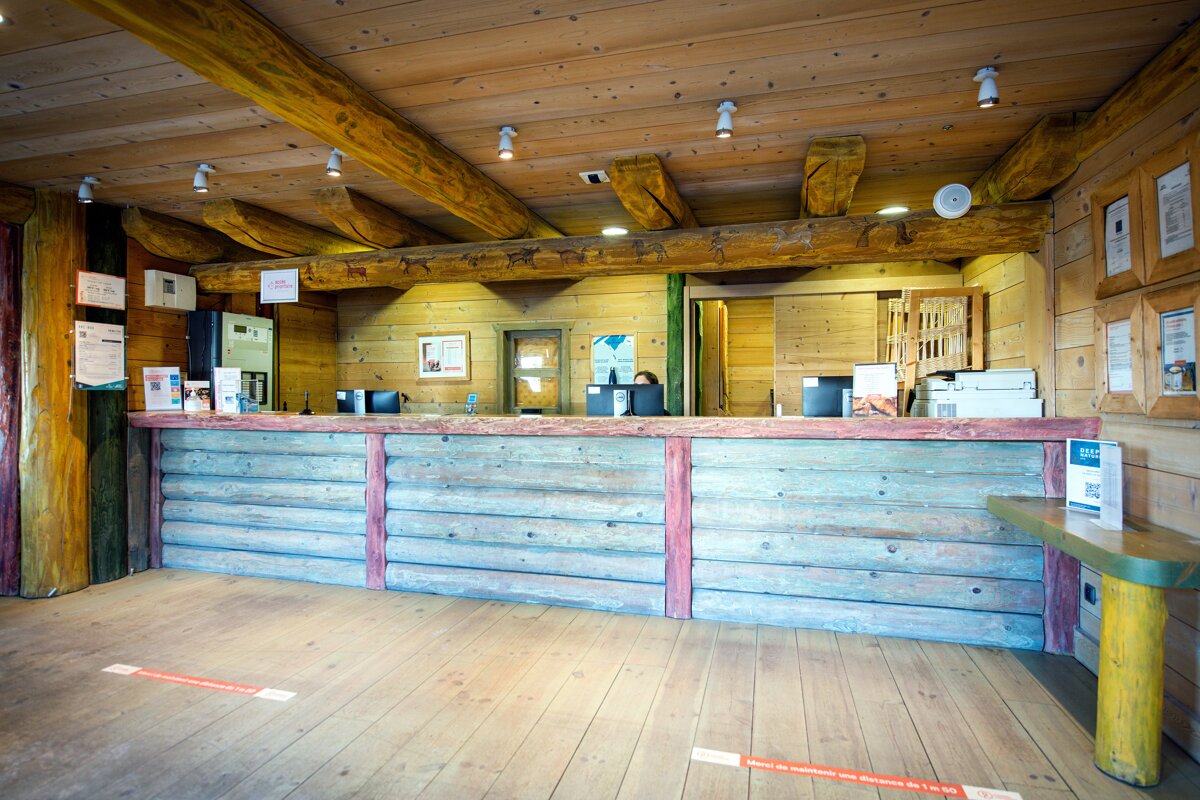 A wooden reception desk with a sign on the wall that says ' a ' on it