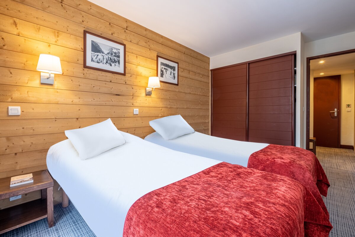 A hotel room with two beds and two pictures on the wall