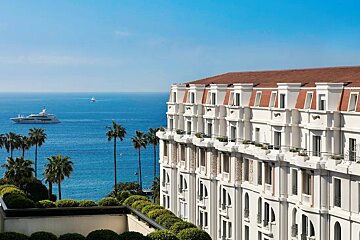 A large white building overlooking the ocean with a boat in the distance