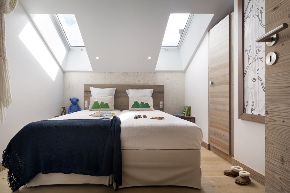 A bedroom with two beds and a skylight on the ceiling