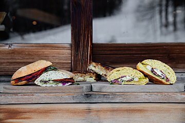 Three sandwiches are sitting on a wooden cutting board